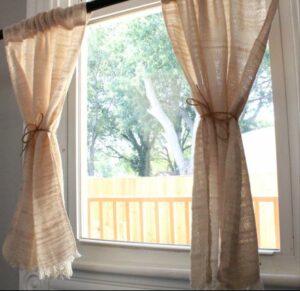 Natural colored bistro curtains in sunny window