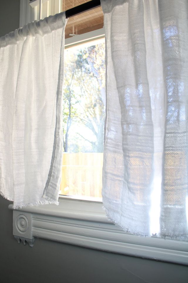 White handwoven curtains hanging straight in a window. Jacqueline's Textiles handwoven fabric in NOVA.